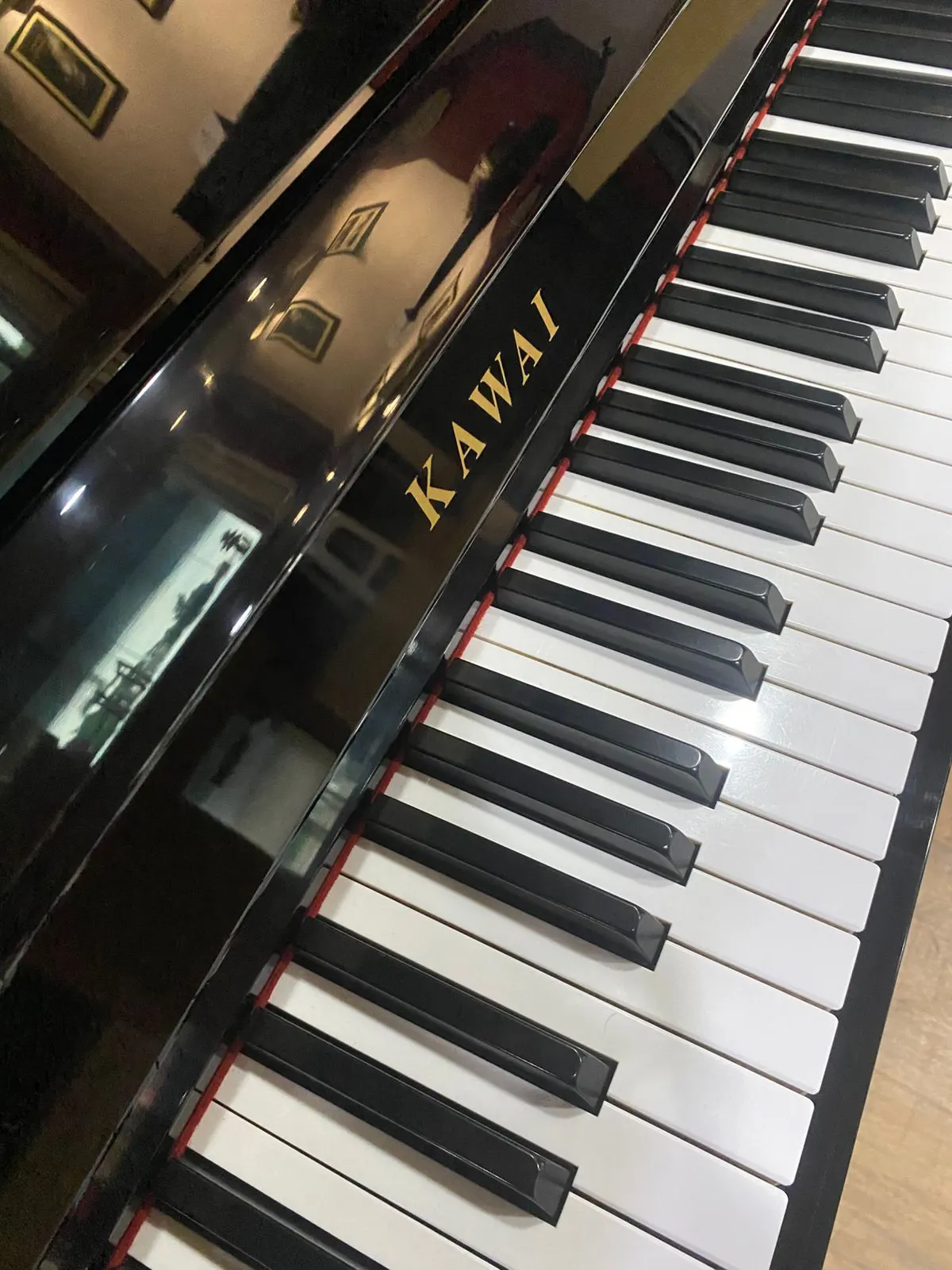 Upright piano Kawai K18E dengan finishing hitam glossy, desain minimalis, dan kualitas suara hangat serta seimbang untuk latihan dan penggunaan harian.